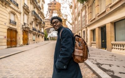 Young,African,Man,With,Glasses,And,Backpack,Smiles,Confidently,While
